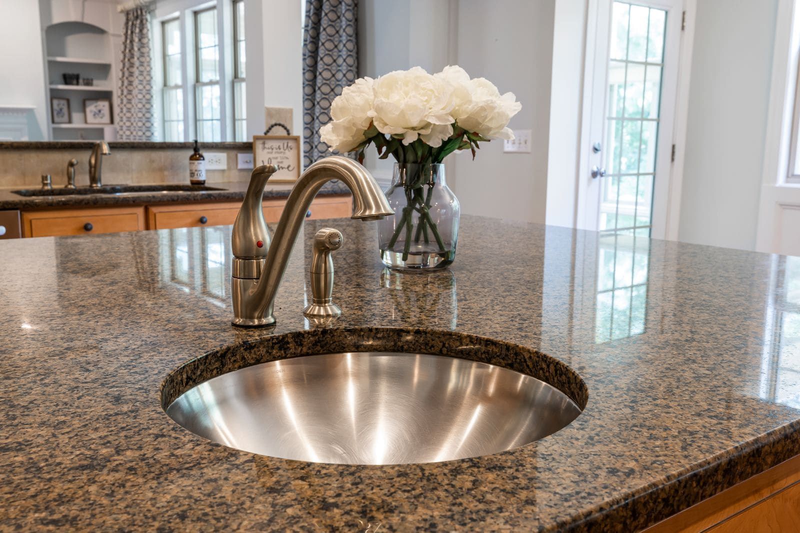 Polished speckled granite kitchen countertop with an undermount stainless sink